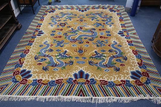 A Chinese carpet, the apricot field with five indigo dragons with a polychrome banded border, 10ft by 8ft 1in.